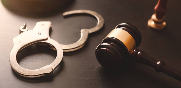 A pair of handcuffs sits on a table next to a gavel.