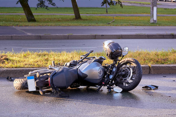 Una motocicleta yace de lado sobre el pavimento.