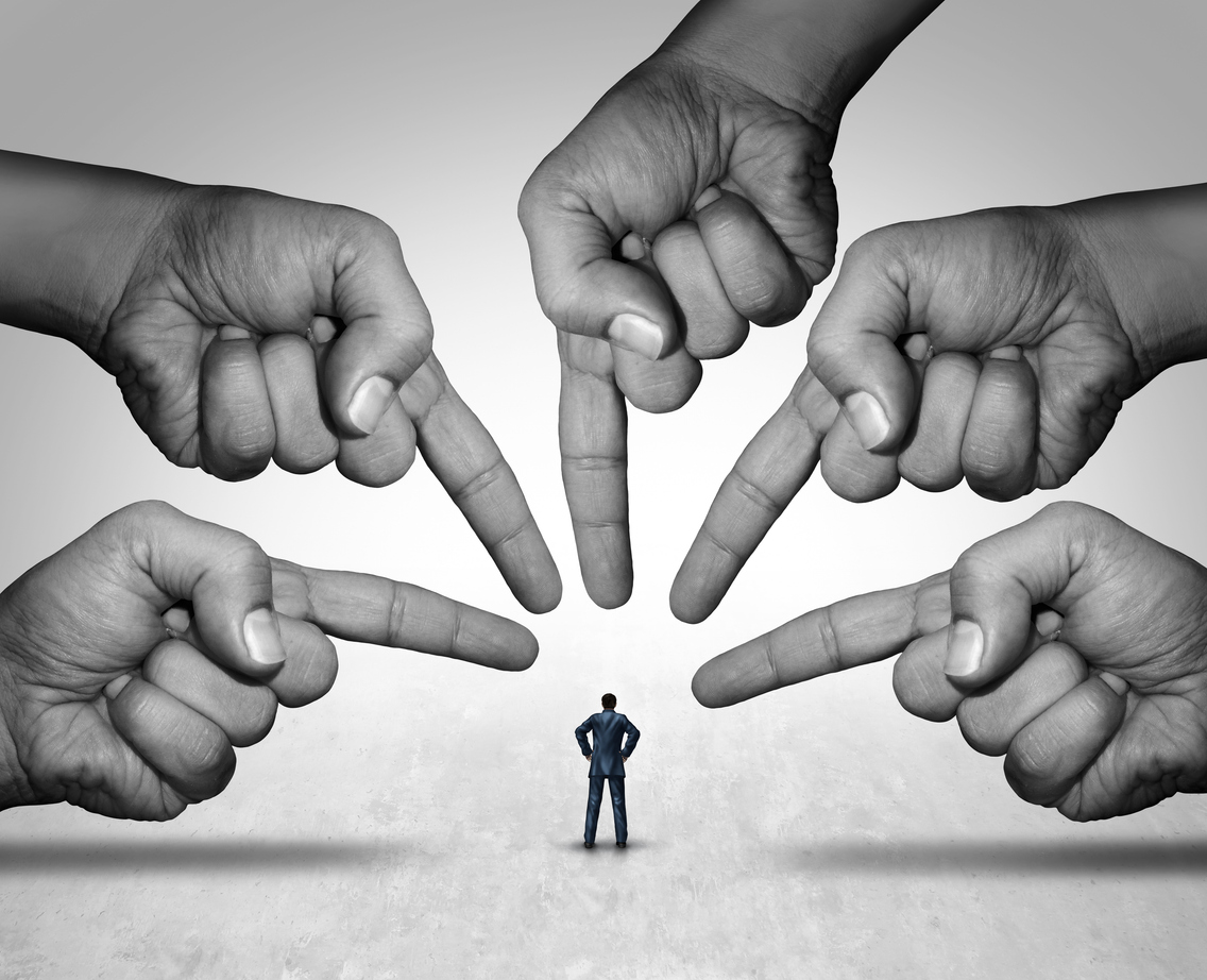 A series of hands pointing fingers at a figure in a suit.